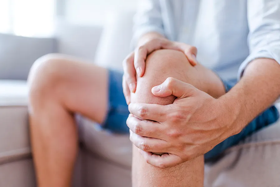 Adult holding knee joint with visible discomfort, representing osteoarthritis treated with PRP injection